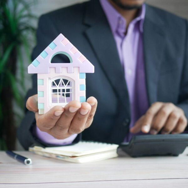 A male holding a small dummy house